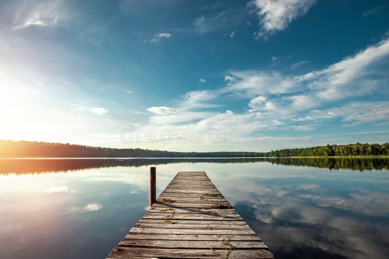 Wooden pier on the background of a beautiful lake summer dawn landscape. Copy space