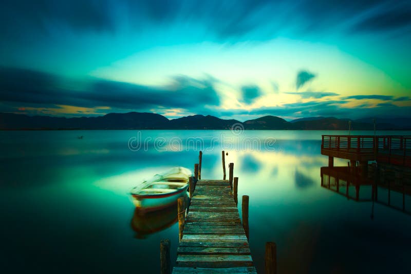 Wooden pier or jetty and a boat on a lake sunset. Versilia Tuscany, Italy