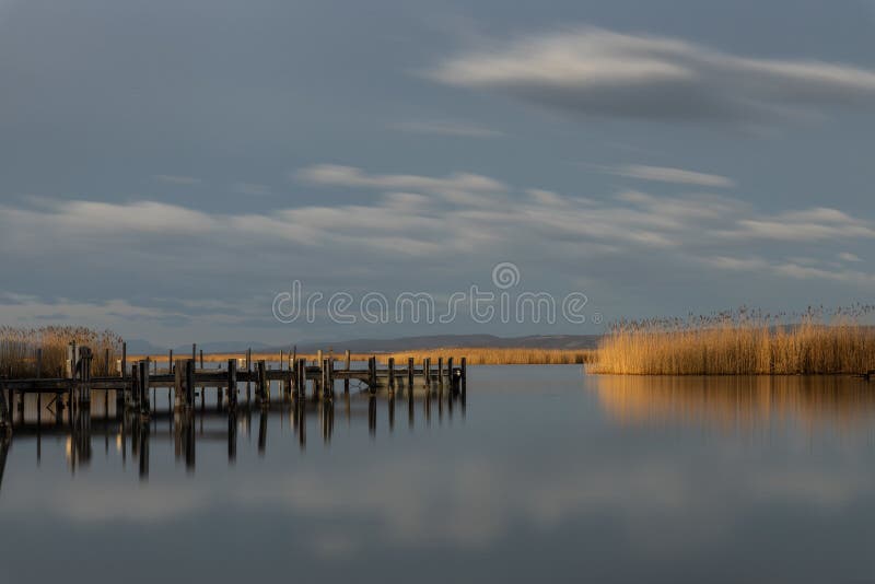 Wooden pier near the sea reflecting on it under the beautiful cloudy sky. A wooden pier near the sea reflecting on it under the beautiful cloudy sky stock image Wooden pier near the sea reflecting on it under the beautiful cloudy sky. A wooden pier near the sea reflecting on it under the beautiful cloudy sky stock image