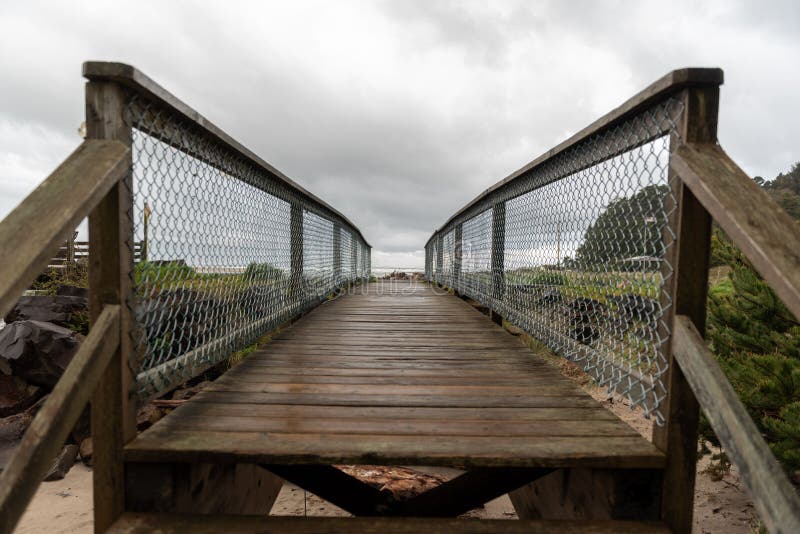 A wooden pier on rocks in the Siletz Bay along the Oregon coast, USA on a cloudy day