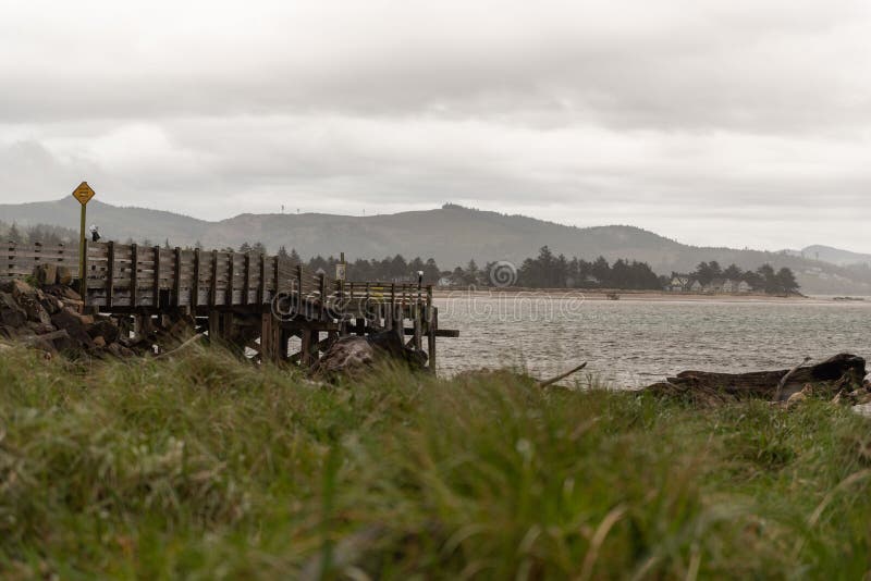 A wooden pier on rocks in the Siletz Bay along the Oregon coast, USA on a cloudy day