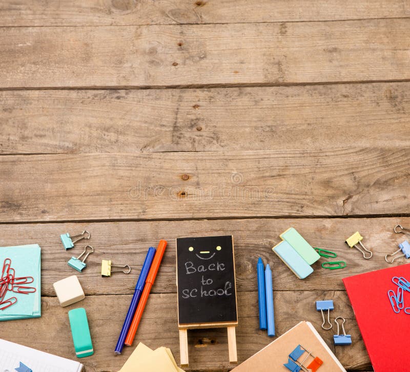 plaque with the inscription & x22;Back to school& x22; near notepads, papers and other stationery on brown wooden table