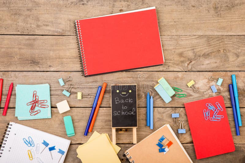 plaque with the inscription & x22;Back to school& x22; near notepads, papers and other stationery on brown wooden table