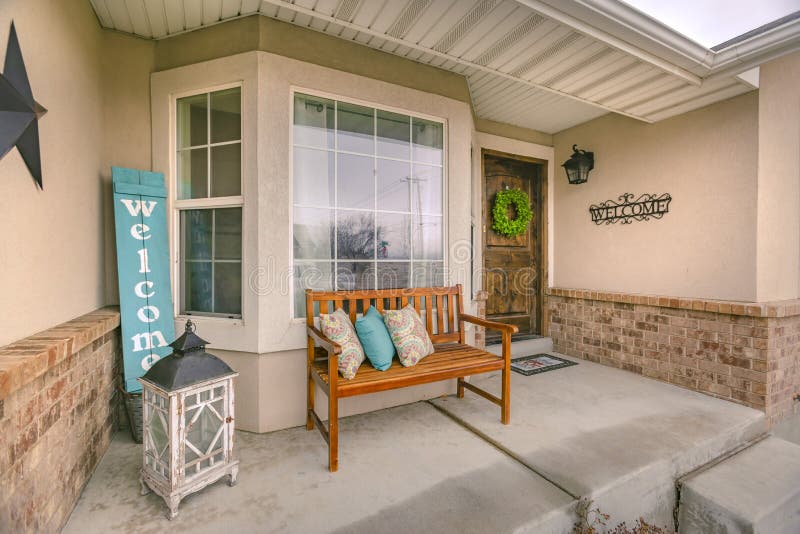 Wooden Porch Bench with Pillows Against the Shiny Front Window