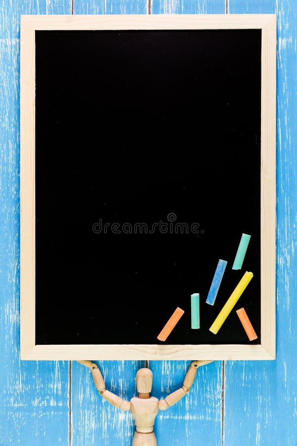 Wooden puppet is lifted Blank blackboard and color chalk on wood royalty free stock photo
