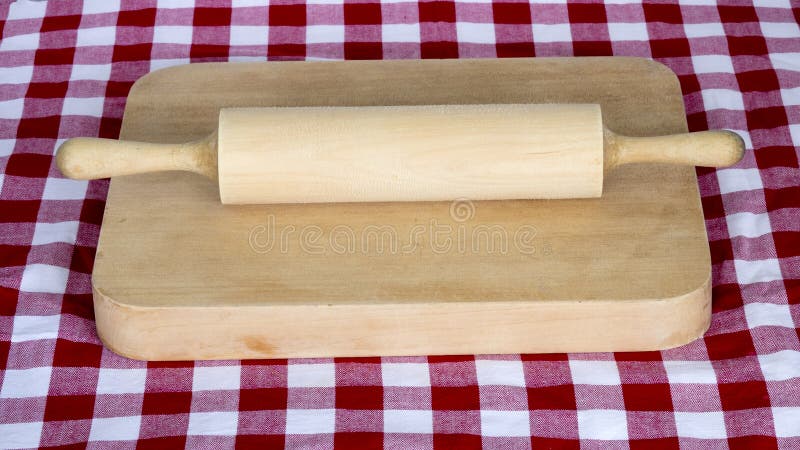 Wooden rolling pin on a board with chequered table cloth stock photo Wooden rolling pin on a board with chequered table cloth stock photo