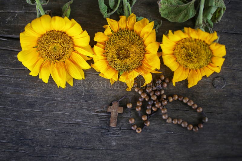 Wooden Rosary with Jesus Christ Cross Crucifix and three beautiful sunflwoers blossom arrangement on rustic table background. royalty free stock photos Wooden Rosary with Jesus Christ Cross Crucifix and three beautiful sunflwoers blossom arrangement on rustic table background. royalty free stock photos