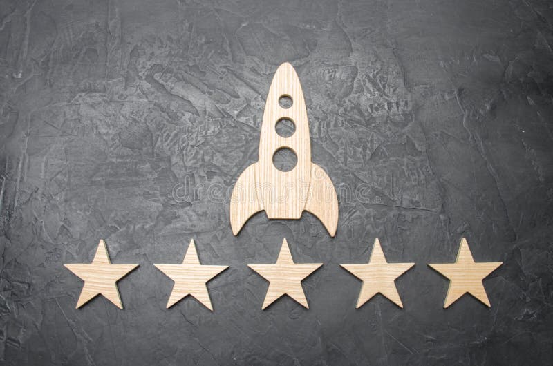 A wooden space rocket and five stars on a concrete background. The concept of space travel, commercial launches into space. Tourist flights to the orbit of the star and the moon. Future technologies.