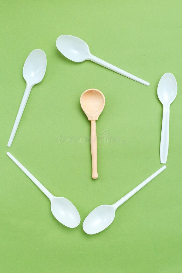 Wooden spoon with plastic alternatives on green background. Vertical. Organic concept royalty free stock photos Wooden spoon with plastic alternatives on green background. Vertical. Organic concept royalty free stock photos