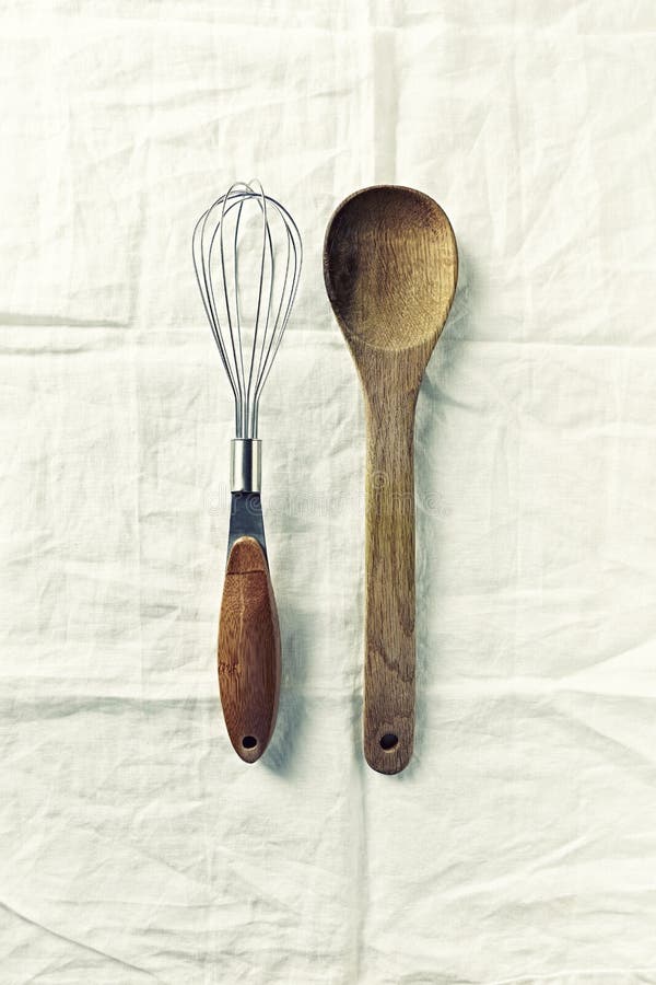 Wooden spoon and whisk on white linen cloth