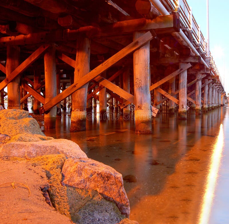 Wooden support of pier bridge over river and rock