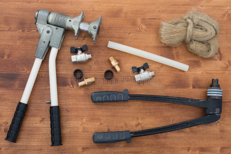 On the Wooden Surface is a Set of Tools for Crimping Water Pipes and