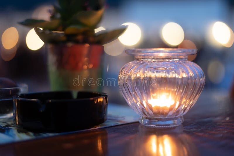 Wooden Table with Ashtray and Plant Illuminated by Candle Light Stock