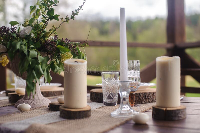 Wooden table set with candles and flowers outdoors stock photos Wooden table set with candles and flowers outdoors stock photos