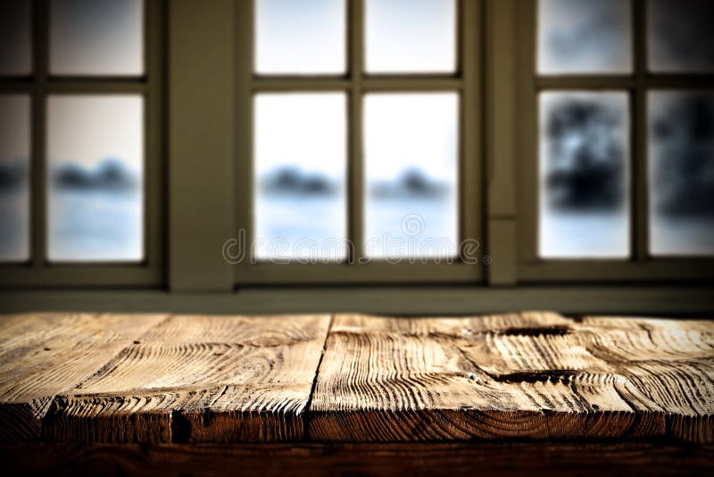 Kitchen wooden table top with space for products and decorations. Snowy winter outside the window.