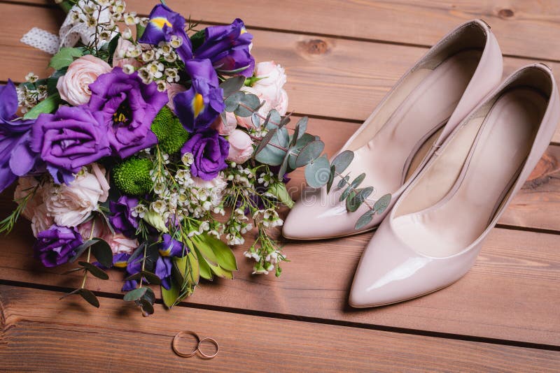 On a wooden table a wedding bouquet with green leaves, purple and white flowers, wedding rings royalty free stock photo On a wooden table a wedding bouquet with green leaves, purple and white flowers, wedding rings royalty free stock photo