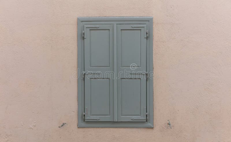Wooden window with grey shutters, closed, on painted wall background stock photos Wooden window with grey shutters, closed, on painted wall background stock photos