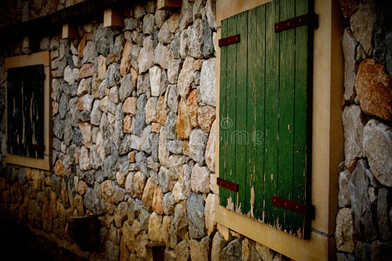 Two Wooden window in a stoned wall, dark green painted wood