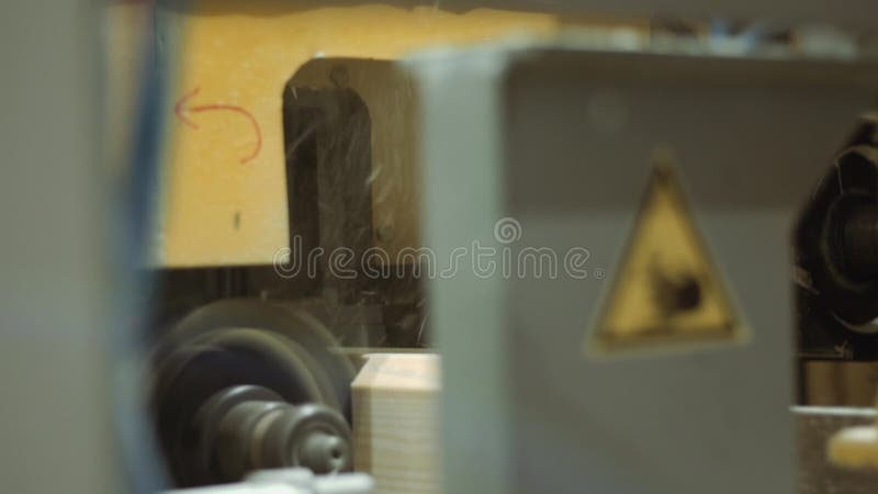 Woodwork machine cuts furrow on wooden block at sawmill facility