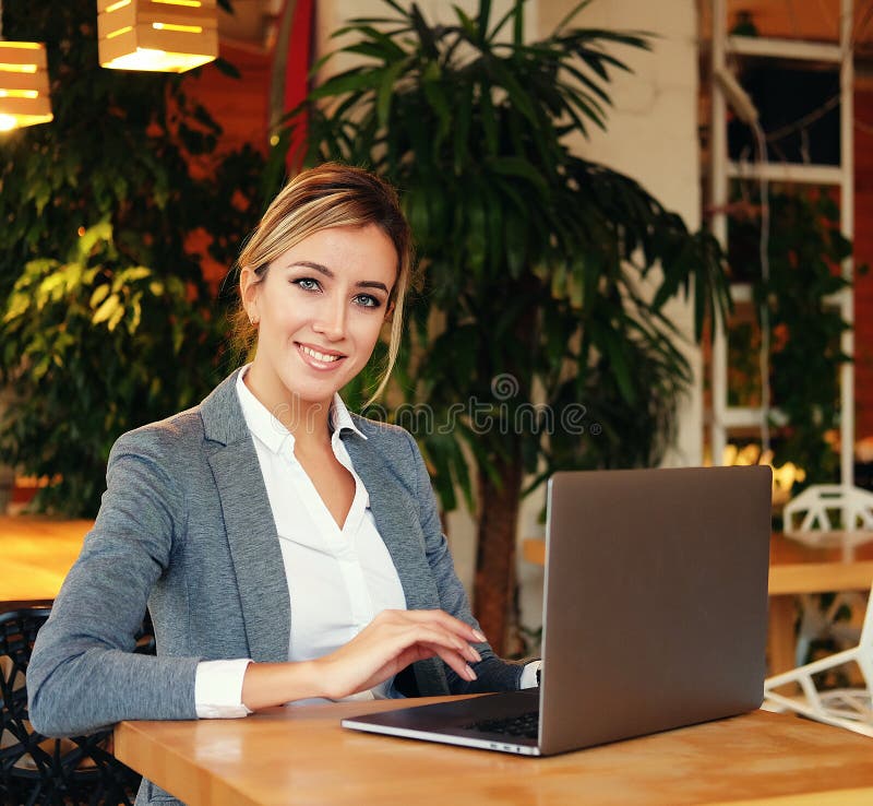 Wooman di affari facendo uso del computer portatile al caffè Giovane bello sitti della ragazza immagine stock Wooman di affari facendo uso del computer portatile al caffè Giovane bello sitti della ragazza immagine stock