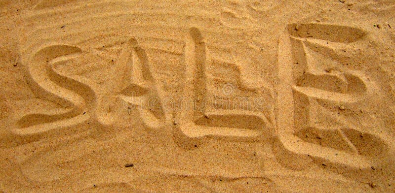 Word sale written by a hand on beach sand.