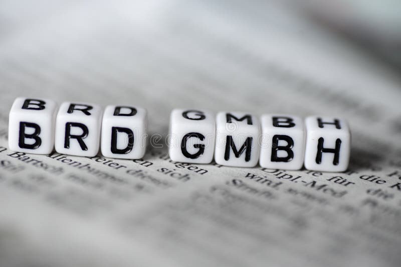 Word BRD GMBH formed by wood alphabet blocks on newspaper