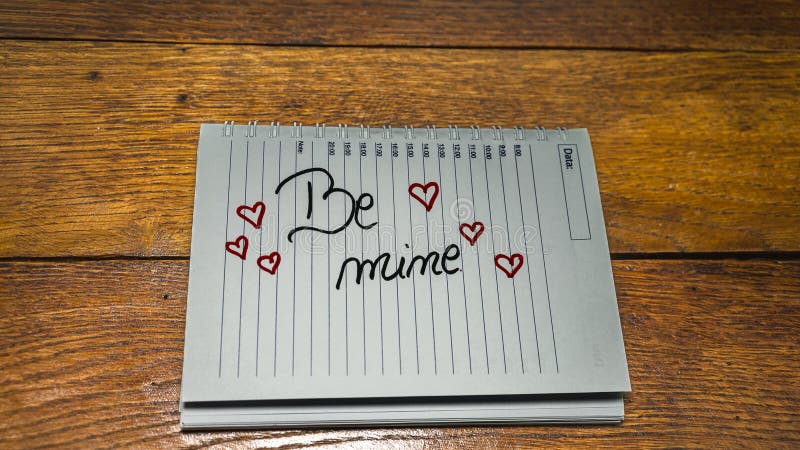 Be mine, writing love text on paper, lovely message. Text on spiral agenda. Romantic, love concept. Valentine`s day. Be mine, writing love text on paper, lovely message. Text on spiral agenda. Romantic, love concept. Valentine`s day