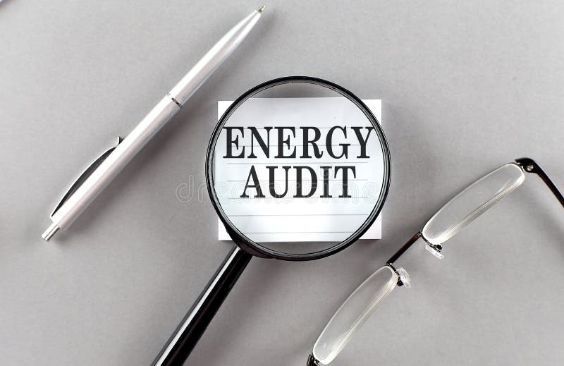 Word energy audit on sticky through magnifier on cinza background foto de stock royalty free
