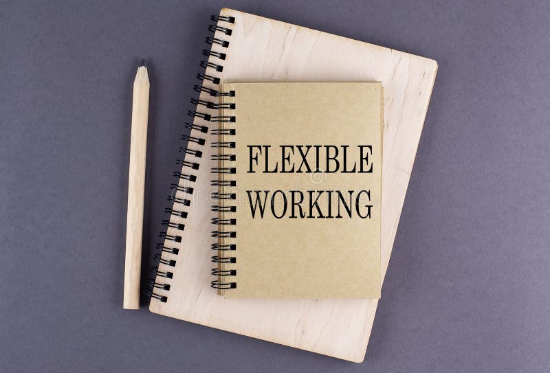 Word FLEXIBLE WORKING a notebook with pencil on the grey background royalty free stock image