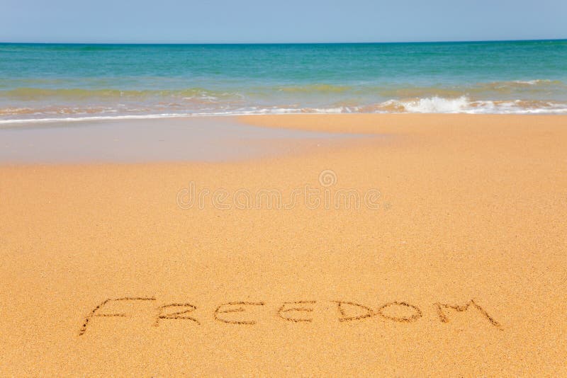 The word Freedom written on the beach sand