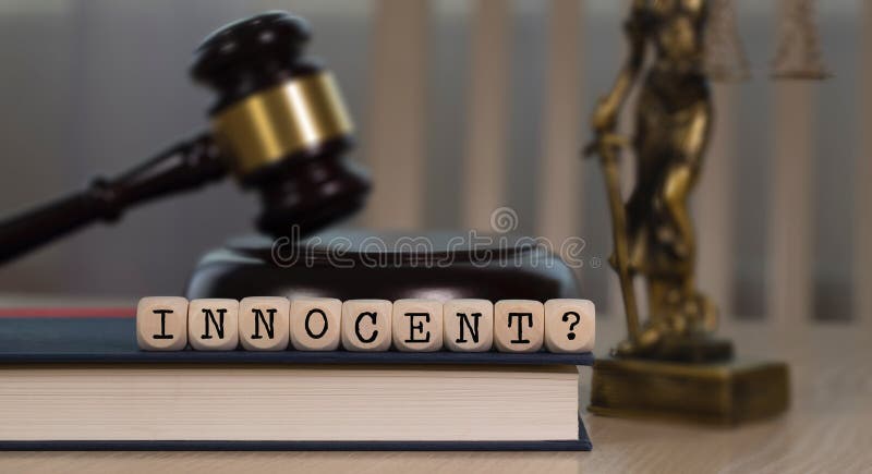 Word INNOCENT composed of wooden dices. Wooden gavel and statue of Themis in the background stock photos Word INNOCENT composed of wooden dices. Wooden gavel and statue of Themis in the background stock photos
