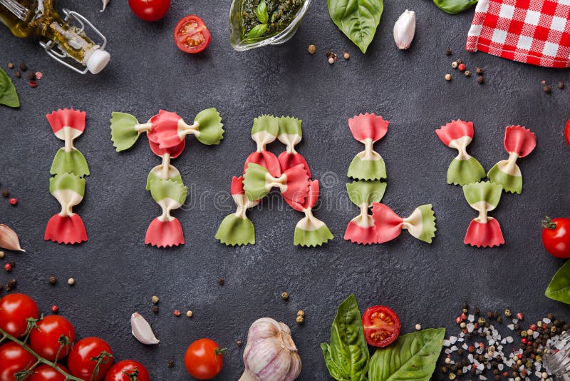 Word Italy from farfalle pasta with cherry tomatoes, garlic, basil, pesto, pepper mix, salt and napkin stock image Word Italy from farfalle pasta with cherry tomatoes, garlic, basil, pesto, pepper mix, salt and napkin stock image