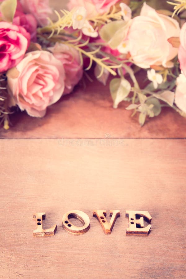 Word Love with rose flower on wood table