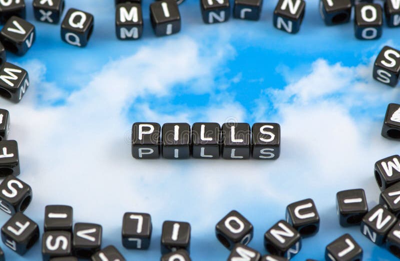The Word Pills is Lined with White Capsule Tablets on a Blue Stock
