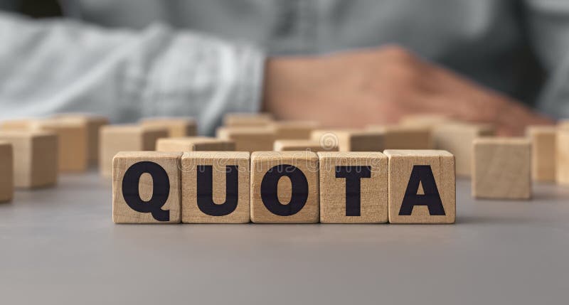 The word QUOTA made from wooden cubes. Shallow depth of field on the cubes