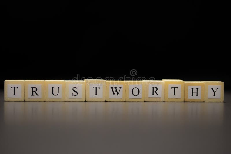 The word TRUSTWORTHY written on wooden cubes, isolated on a black background