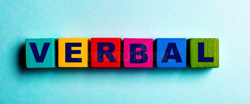 The word VERBAL is written on multicolored bright wooden cubes on a light blue background