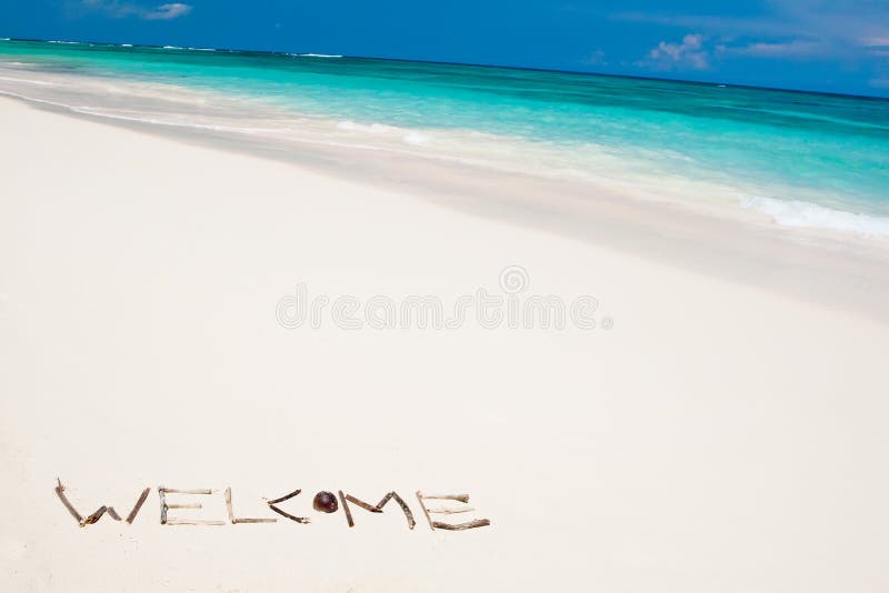 Word welcome on a white sand beach near blue ocean