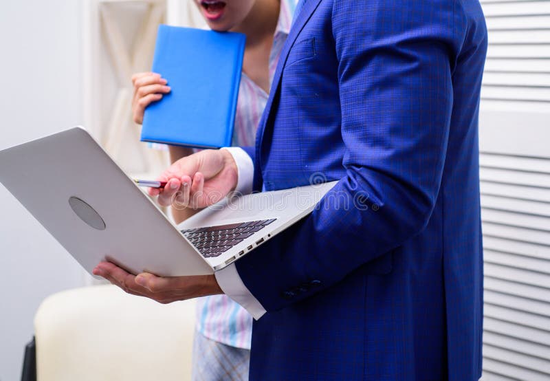 Work culture. Happy creative team working at office. Two joyful young people in formalwear holding laptop, book and stock photos Work culture. Happy creative team working at office. Two joyful young people in formalwear holding laptop, book and stock photos