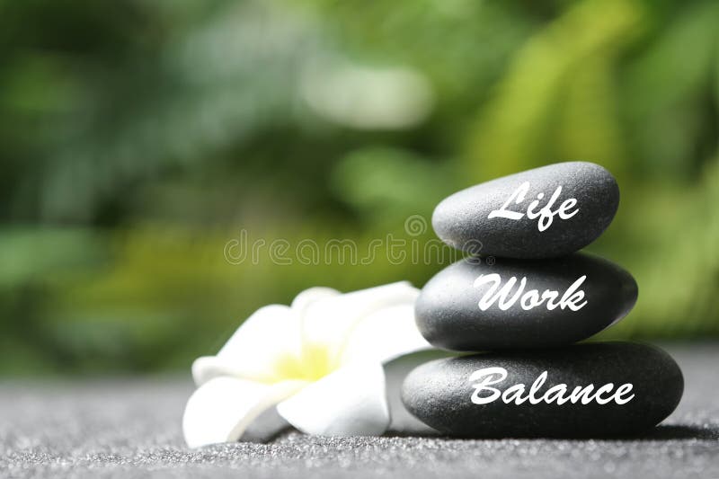 Work-life balance. Stacked stones and plumeria flower on sand