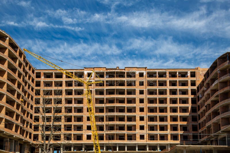 Work in progress on a new apartment block. Tall building under construction with cranes. Construction Site of New Building