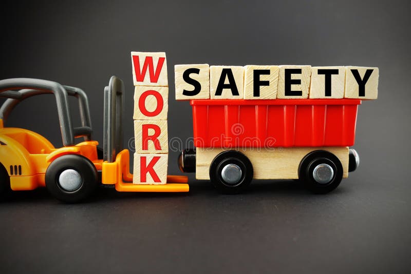 Work safety concept with wooden blocks on orange forklift with dark background stock photo Work safety concept with wooden blocks on orange forklift with dark background stock photo