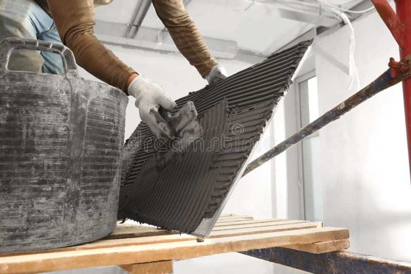Worker Applying Cement on Tile for Installation in Room, Closeup Stock