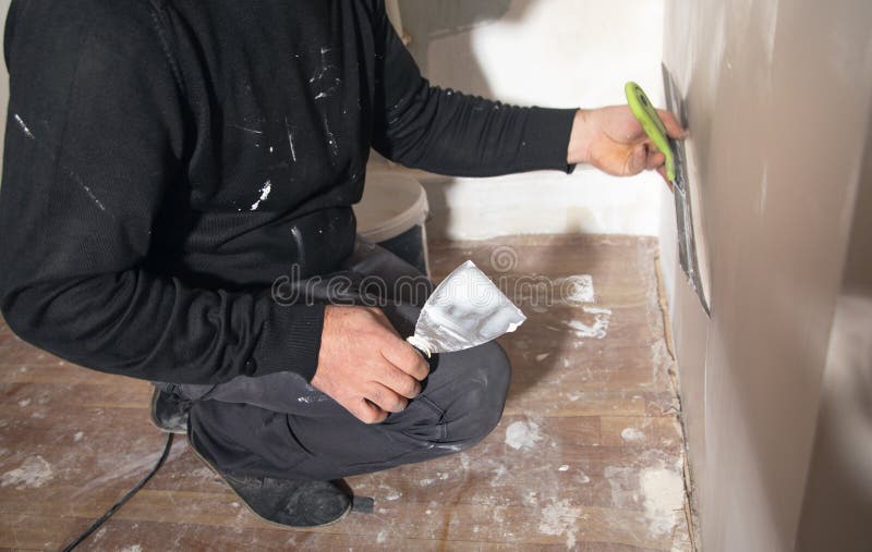 Worker is Applying Putty on a Wall. Renovating House Stock Image