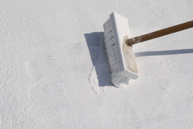 Worker applying white roof coating stock image