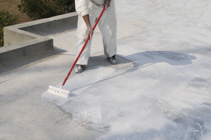 Worker applying white roof coating stock photo
