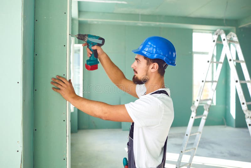 Worker Builder Installs Plasterboard Drywall at a Construction Stock