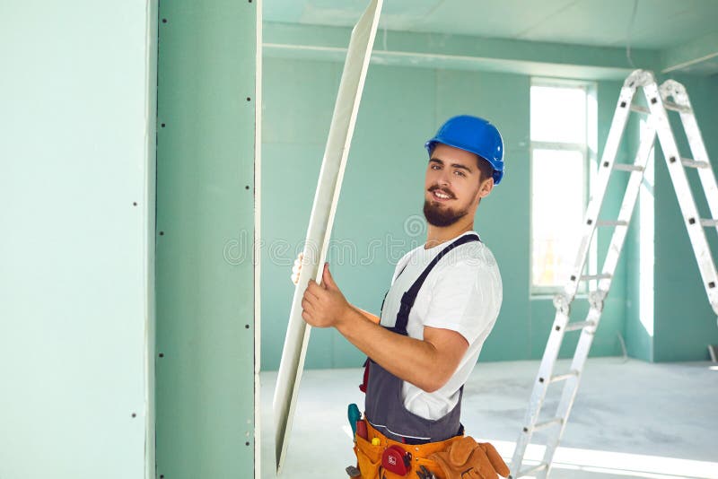 Worker Builder Installs Plasterboard Drywall at a Construction Stock