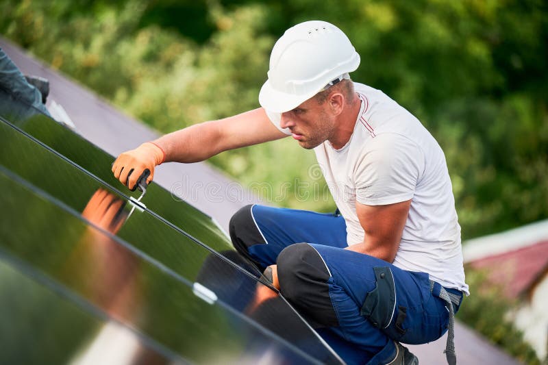 Worker building photovoltaic solar panel system on rooftop of house with help of hex key. royalty free stock image