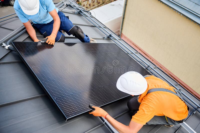 Worker building photovoltaic solar panel system on rooftop of house with help of hex key. stock images